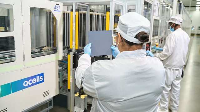 Qcells technicians inspecting a solar cell on the production line